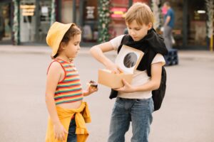 Kids eating colorful sweet and tasty donuts. Children snacking on unhealthy food outdoors.